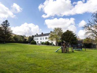 An outdoor area with a house and playground equipment at Cheviot Manor Akeld near Wooler