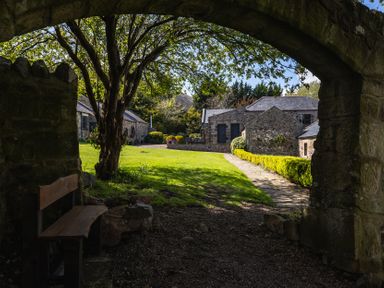 A garden with a stone wall and pathway at Cheviot Manor Akeld near Wooler