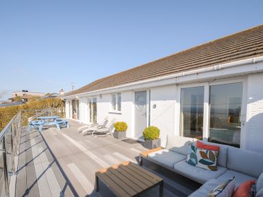 A large outdoor deck with lounge chairs a picnic table and a sofa set at Atlanta near Tintagel