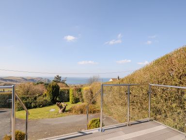 A view of a garden with trimmed hedges and a pathway with the sea and hills visible in the background at Atlanta near Tintagel