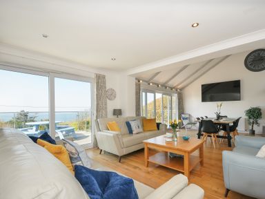 A living room with sofas, a coffee table, a dining table, and sliding glass doors showing an outdoor area at Atlanta near Tintagel