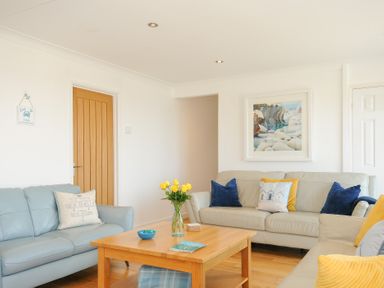 A living room with three sofas a wooden coffee table with flowers and a bowl and cushions on the sofas at Atlanta near Tintagel