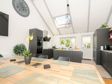 A kitchen with a wooden table and black chairs black cabinets and a skylight at Atlanta near Tintagel