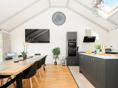 A kitchen with black cabinets dining table with chairs and a wall clock at Atlanta near Tintagel