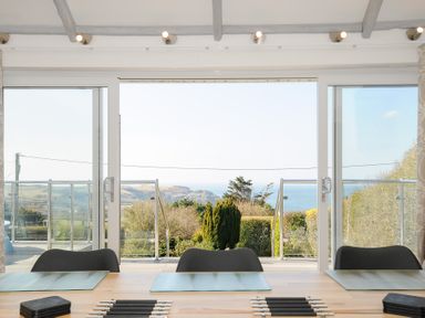 A dining area with a wooden table and chairs facing large sliding glass doors with an outdoor view at Atlanta near Tintagel