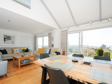 A dining table with placemats and black chairs next to a living area with sofas and a coffee table at Atlanta near Tintagel