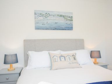 A bedroom with a bed that has white pillows and a decorative cushion with design and two bedside tables with lamps at Atlanta near Tintagel
