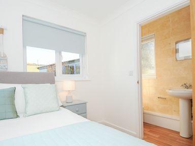 A bedroom with a bed pillows lamp and a side table next to a bathroom at Atlanta near Tintagel