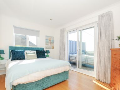 A bedroom with a bed a wooden dresser a window sliding glass doors leading to a balcony at Atlanta near Tintagel