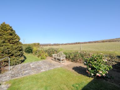 An outdoor garden area with a stone patio bench surrounded by bushes and grass at Atlanta near Tintagel