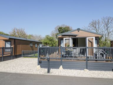 A small wooden cabin with a fenced deck patio and outdoor furniture at Casa De Rhu in Evesham