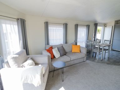 A living room with a gray sofa and armchair a small round table and a dining table with chairs at Casa De Rhu in Evesham