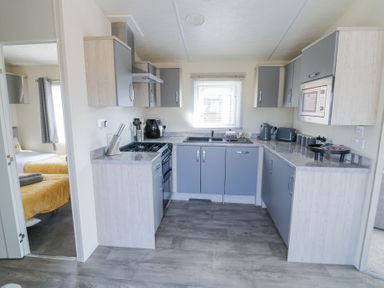 A kitchen with grey cabinets a stove a microwave and kitchen utensils at Casa De Rhu in Evesham