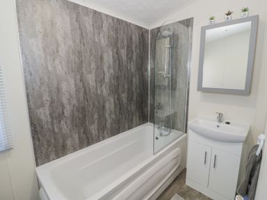 A bathroom with a bathtub shower sink and mirror cabinet at Casa De Rhu in Evesham