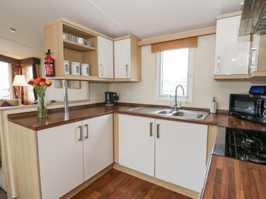 A kitchen with white cabinets wooden countertop a double sink a microwave and a kettle at 21 Bay View in Maenygroes near New Quay Ceredigion