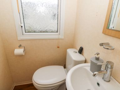 A small bathroom with a toilet sink soap dispenser and a frosted window at 21 Bay View in Maenygroes near New Quay Ceredigion