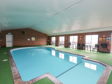 An indoor swimming pool with a brick wall and tables with chairs along the side at 21 Bay View in Maenygroes near New Quay Ceredigion