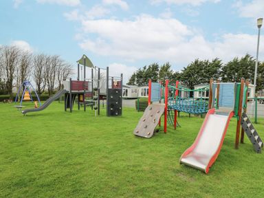 A playground with slides climbing walls and swings on grass at 21 Bay View Maenygroes near New Quay Ceredigion