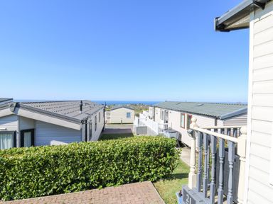 A row of static caravans with a hedge in front and a view of the sea at 21 Bay View in Maenygroes near New Quay Ceredigion