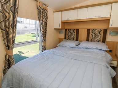 A bedroom with a double bed and patterned curtains by a window at 21 Bay View in Maenygroes near New Quay Ceredigion