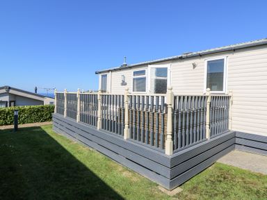 An exterior view of a mobile home with a fenced deck surrounded by grass at 21 Bay View in Maenygroes near New Quay Ceredigion
