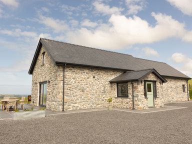 A house with stone exterior and patio furniture at Golygfa Cwrt Near Bontgoch and Penrhyncoch