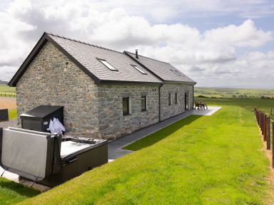 A stone house with a hot tub and outdoor furniture at Golygfa Cwrt Near Bontgoch and Penrhyncoch