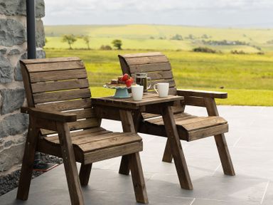 An outdoor seating area with wooden chairs and table at Golygfa Cwrt near Bontgoch and Penrhyncoch
