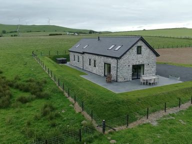 A house with a patio and hot tub near green fields at Golygfa Cwrt near Bontgoch and Penrhyncoch