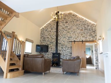 A living room with a stone wall and a television at Golygfa Cwrt near Bontgoch and Penrhyncoch
