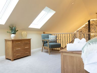 A bedroom with a chest of drawers and a sofa chair at Golygfa Cwrt near Bontgoch and Penrhyncoch
