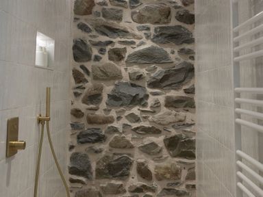 A shower area with a stone wall and plumbing fixtures at Golygfa Cwrt near Bontgoch and Penrhyncoch
