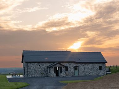A stone house with a driveway and outdoor bench at Golygfa Cwrt near Bontgoch and Penrhyncoch