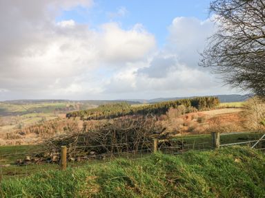 A view of fields hills and trees with a wire fence in the foreground at Blaidd Bach in Carmarthen