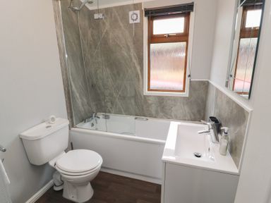 A bathroom with a toilet sink bathtub shower and a window at Lakeside 18 in Carnforth