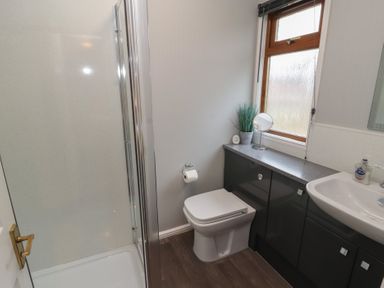 A bathroom with a shower enclosure toilet sink cabinets and a window at Lakeside 18 in Carnforth