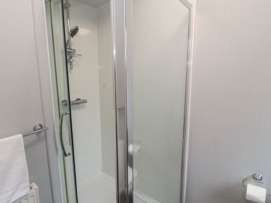 A bathroom with a shower enclosure towel rack and toilet paper holder at Lakeside 18 in Carnforth