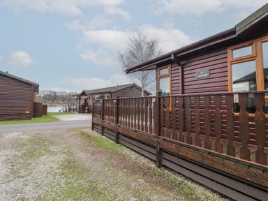 A row of wooden cabins with porches near a lake at Lakeside 18 in Carnforth