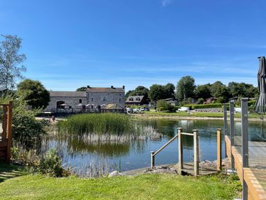 A lakeside view with reeds water and houses in the background at Lakeside 18 in Carnforth