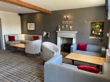 A sitting room with armchairs sofas wooden tables a fireplace and wall decorations at Lakeside 18 in Carnforth