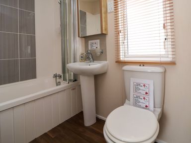 A bathroom with a bathtub shower sink toilet and window blinds at Hazel Park Lodge HP4 in Rhyl