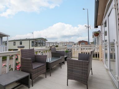 An outdoor patio area with wicker chairs and a table at Hazel Park 11 HP11 in Rhyl