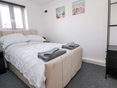 A bedroom with a bed, bedding, towels, and a nightstand at 4 Willow Grove - Freehold Talacre