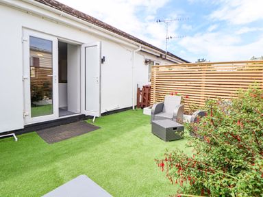 A green garden area with chairs and a table at 4 Willow Grove - Freehold Talacre