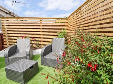 A garden with two chairs and a table surrounded by plants at 4 Willow Grove - Freehold Talacre