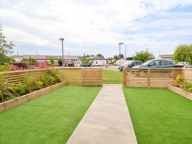 A garden with a pathway and seating area at 4 Willow Grove - Freehold Talacre