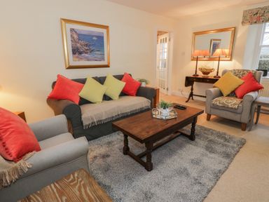 A living room with sofa armchairs coffee table and wall mirror at Eagle Glen Cottage in Kettins near Coupar Angus