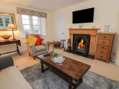 A living room with a fireplace a wooden coffee table and armchairs at Eagle Glen Cottage in Kettins near Coupar Angus