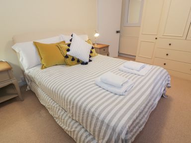 A bedroom with a striped bedspread pillows and folded towels on the bed at Eagle Glen Cottage in Kettins near Coupar Angus