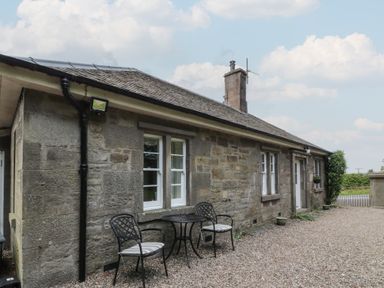 A stone exterior with a table and chairs at Eagle Glen Cottage Kettins near Coupar Angus